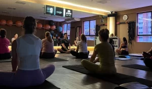 Salão da academia com vários alunos praticando yoga